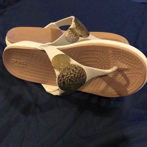 White crocs sandals with gold emblem